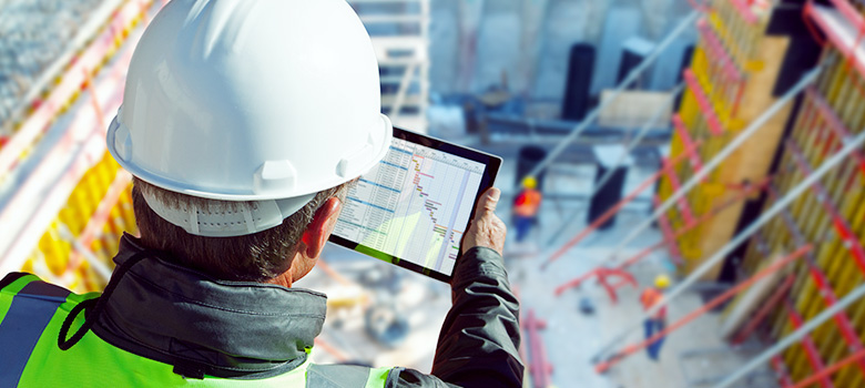 Ingenieur überprüft auf der Baustelle via Tablet Anfragen und Ausschreibungen